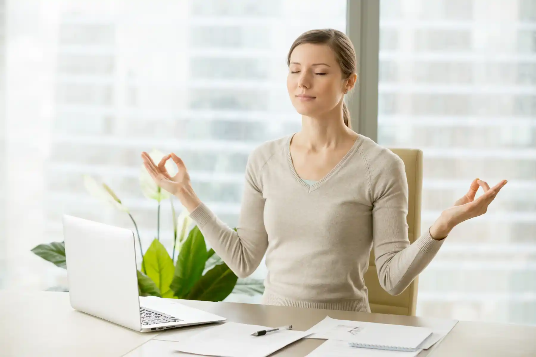 Woman practicing mindfulness meditation at her desk, showing how daily habits like meditation can support brain growth and mental wellness. Save your Brain Wellness