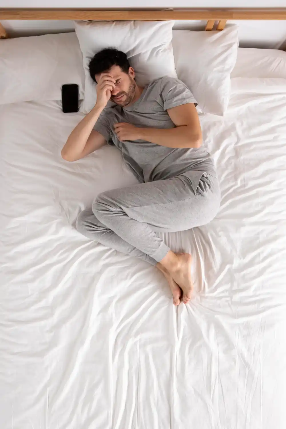 Man suffering from poor sleep lying in bed, showing the mental health impact of sleep deprivation - Save your Brain Wellness
