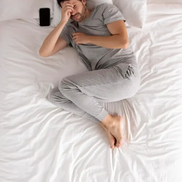 Man suffering from poor sleep lying in bed, showing the mental health impact of sleep deprivation.