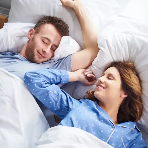 Happy couple sleeping peacefully in bed after successfully completing a sleep restriction therapy program to reset their circadian rhythm