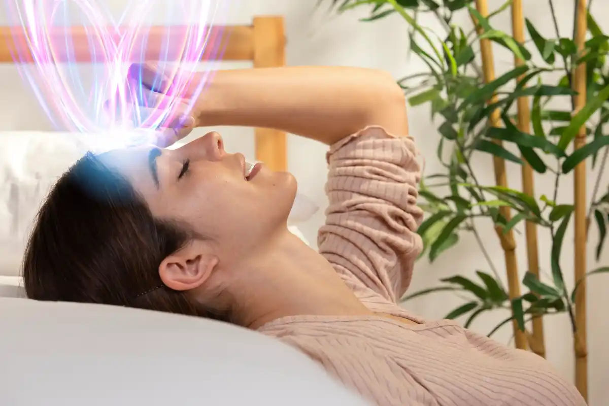 Woman lying peacefully with energy light from forehead, symbolizing emotional healing and brain health through self-compassion