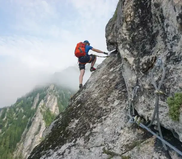 Man climbing steep rocky mountain using safety ropes, symbolizing overcoming mental challenges and unlocking brain motivation.