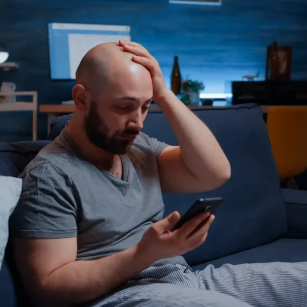 Stressed man overwhelmed by digital addiction and dopamine overload while using smartphone at night