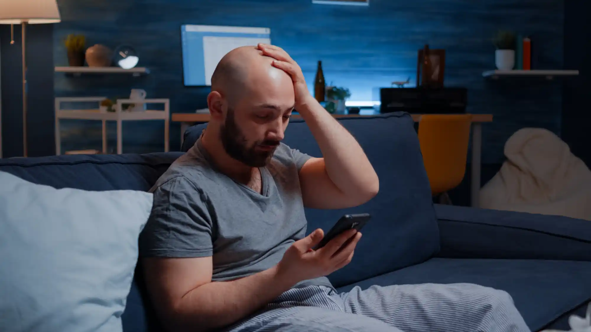 Stressed man overwhelmed by digital addiction and dopamine overload while using smartphone at night